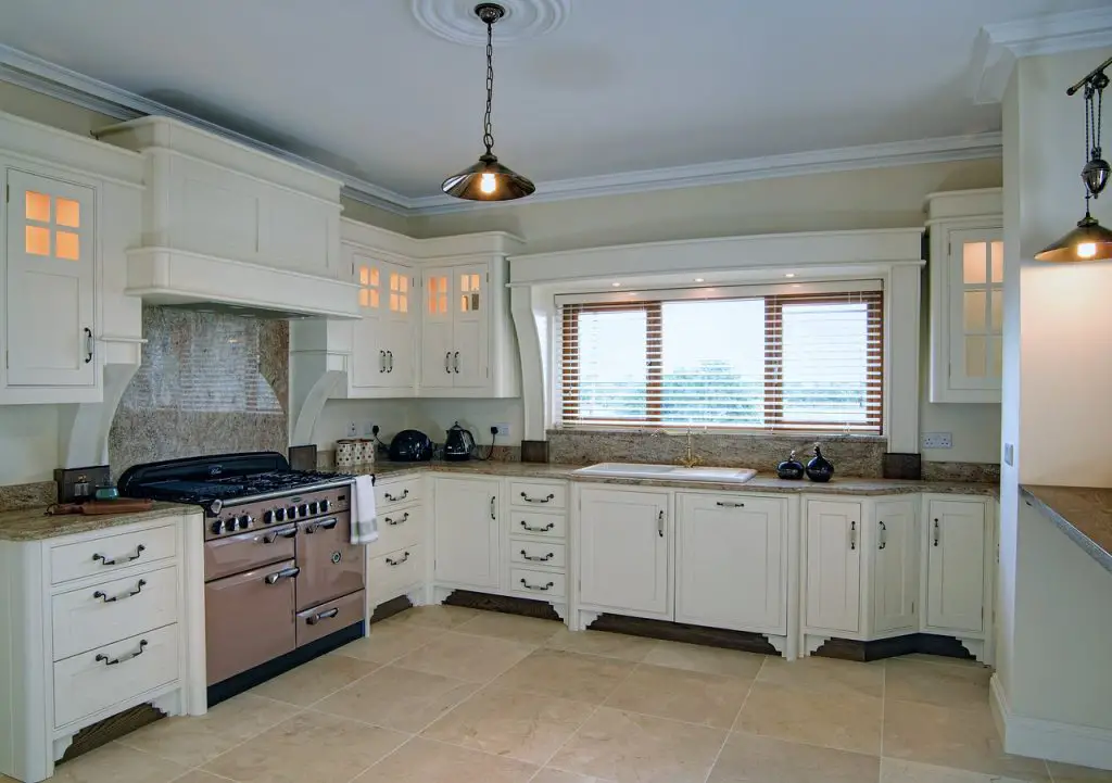 Image of a kitchen painted in white with cabinets, a stove, and range hood above it. Source: kitchen, pixabay