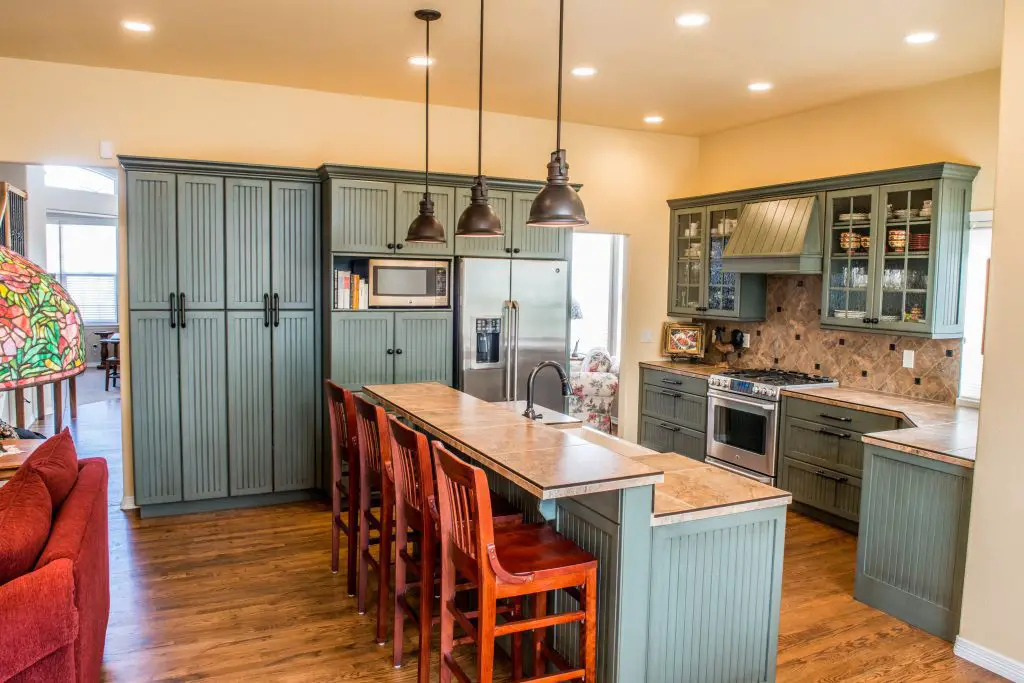 Image of a kitchen with wooden chairs, cabinets, a countertop, and a range hood. Source: Shopify