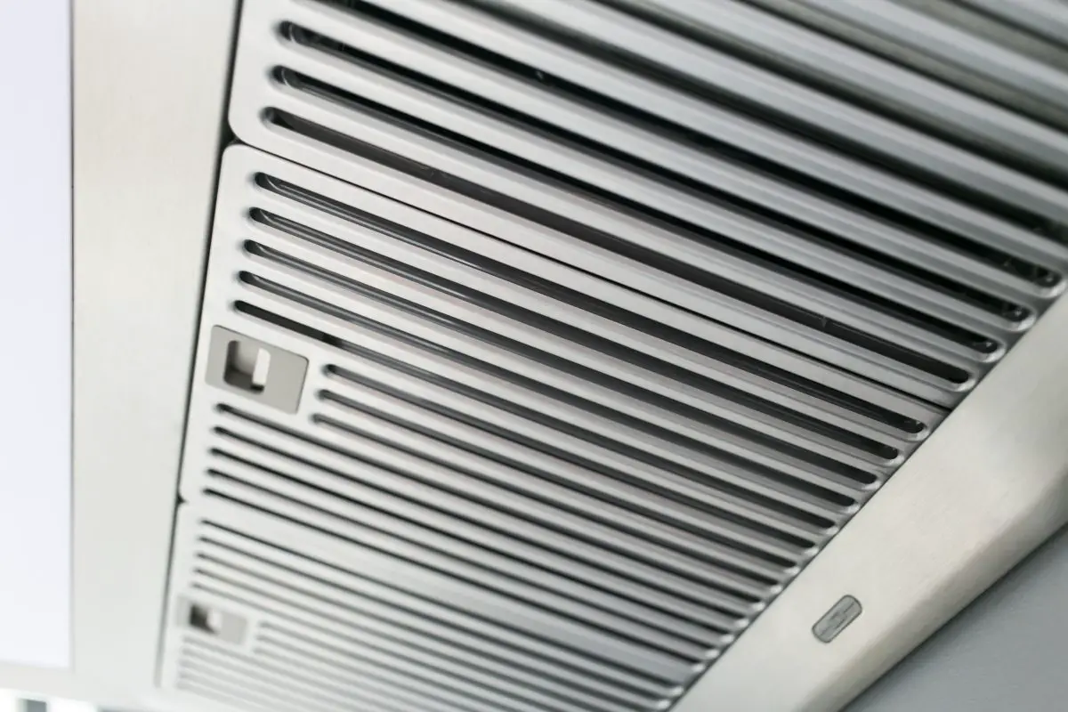 Image of a clean stainless steel range hood baffle filter installed in a wall mount vent hood. Source: adobe stock