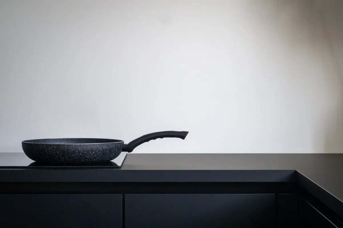Image of a black countertop with an induction cooker and a pan. Source: sven brandsma, unsplash