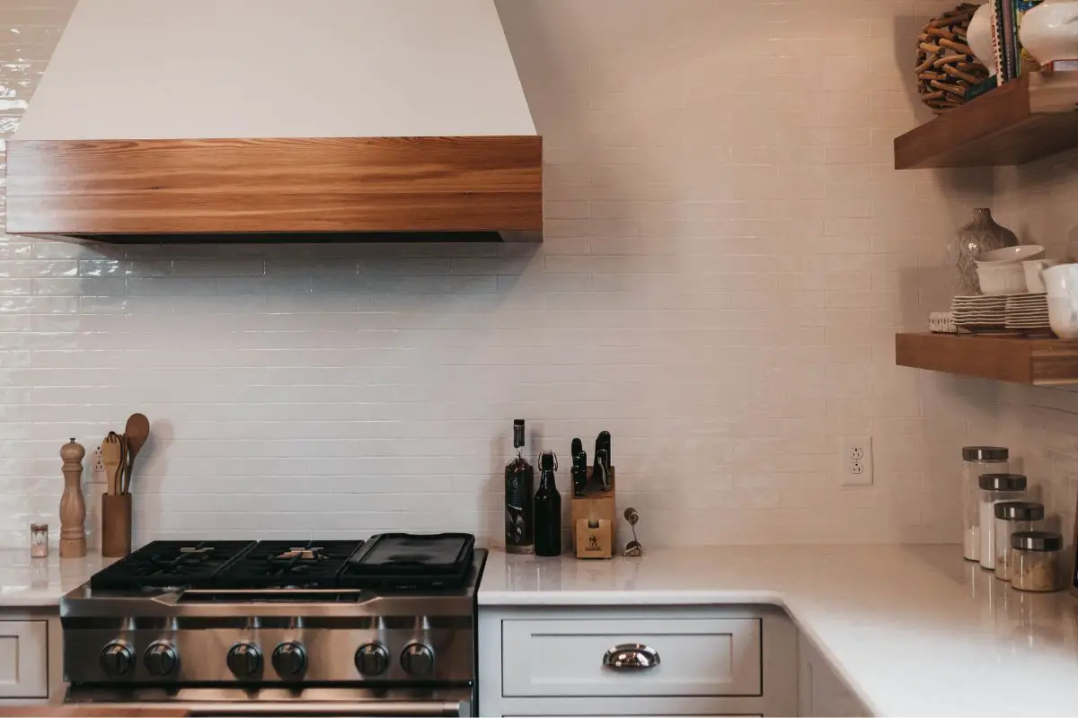Image of a kitchen with a stove a range hood and white countertop. Source: camylla battani, unsplash