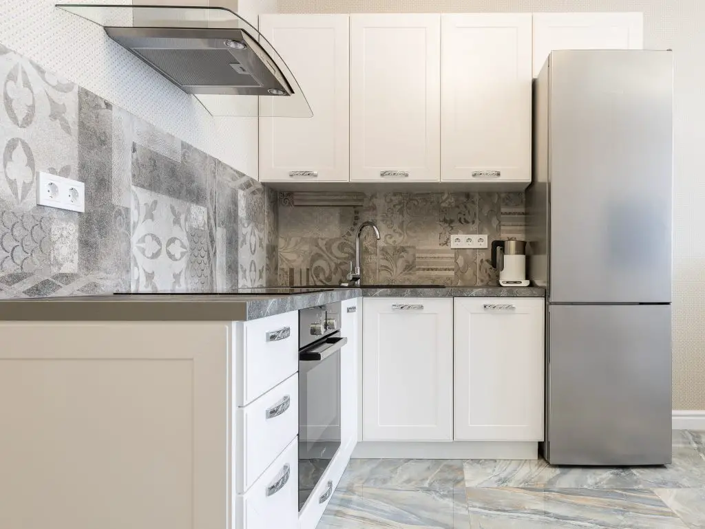 Image of a kitchen with a range hood, a fridge, and gray countertop. Source: max vakhtbovych, pexels