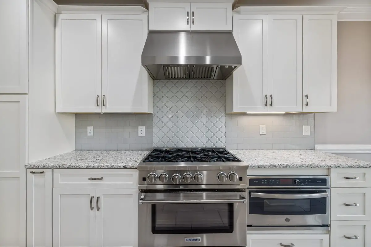 Image of a kitchen with range hood white cabinets and a marble countertop. Source: curtis adams, pexels