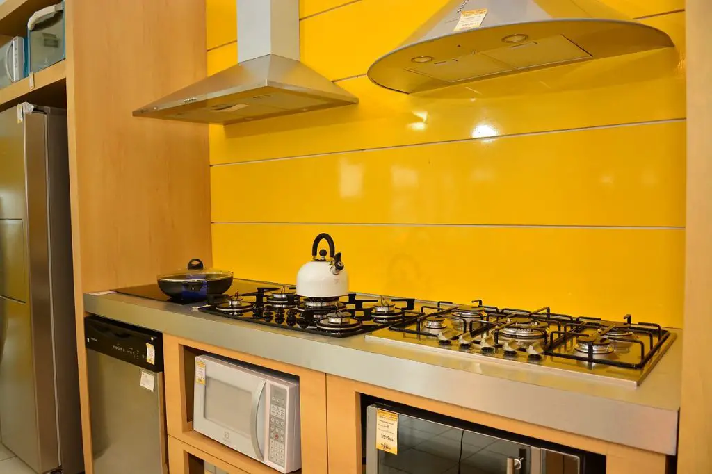 Image of a kitchen with yellow walls, a stove, and a range hood above it. Source: pixabay