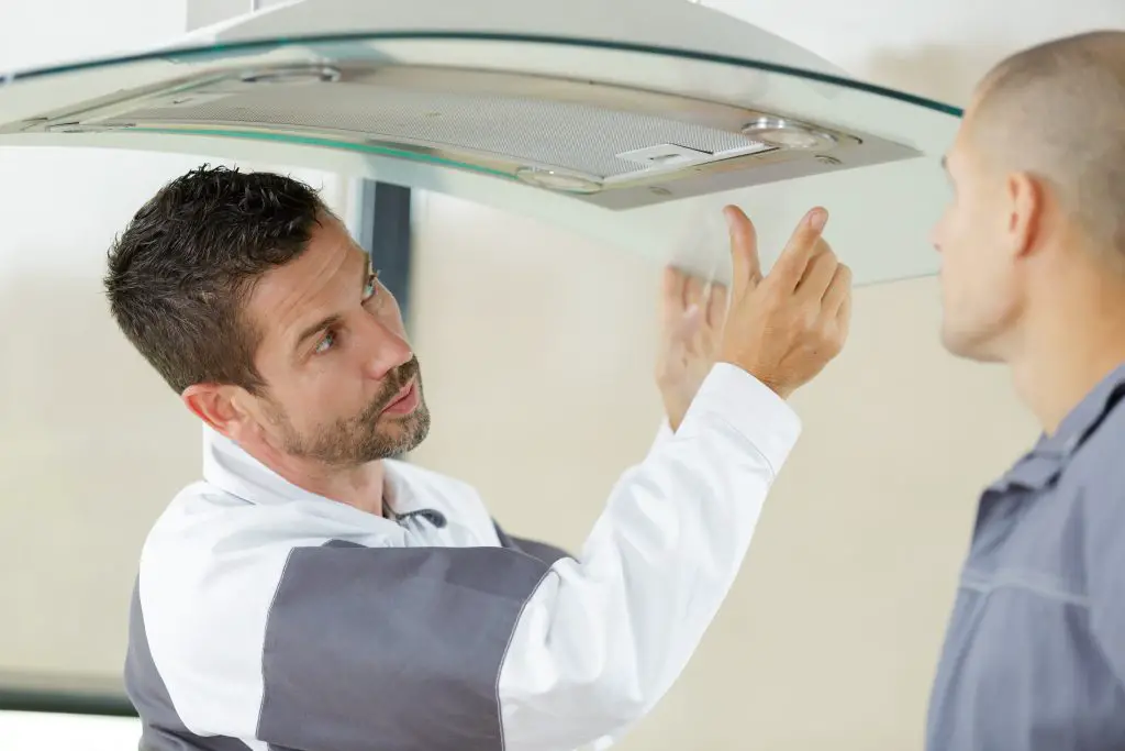 Image of two men inspecting a tempered glass range hood. Source: adobe stock